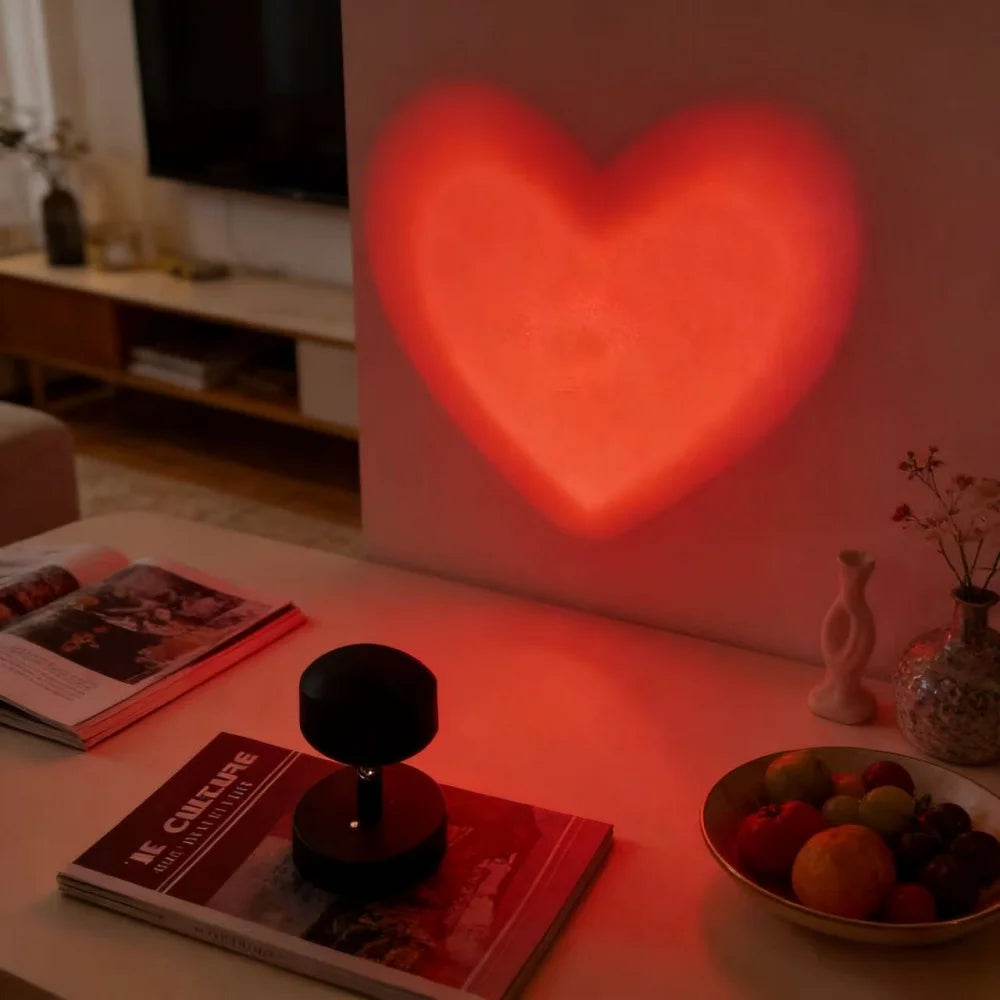 Heart-shaped light projection on a wall with a table and books in the foreground.