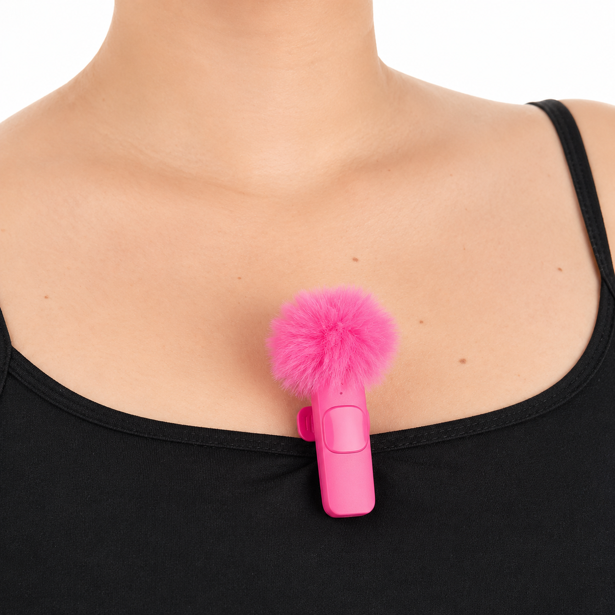 Pink hair clip with fluffy attachment on a person wearing a black top against a white background